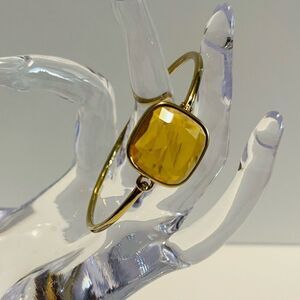 Gold tone bangle bracelet with clasp opening.